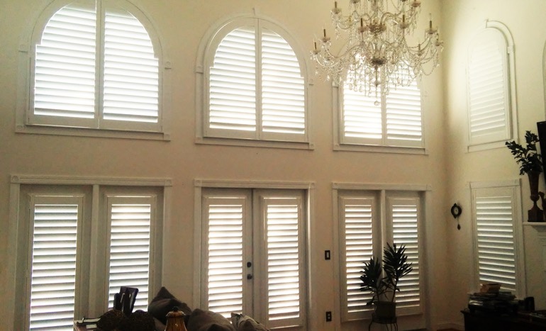 Family room in open concept Tampa home with plantation shutters on high ceiling windows.