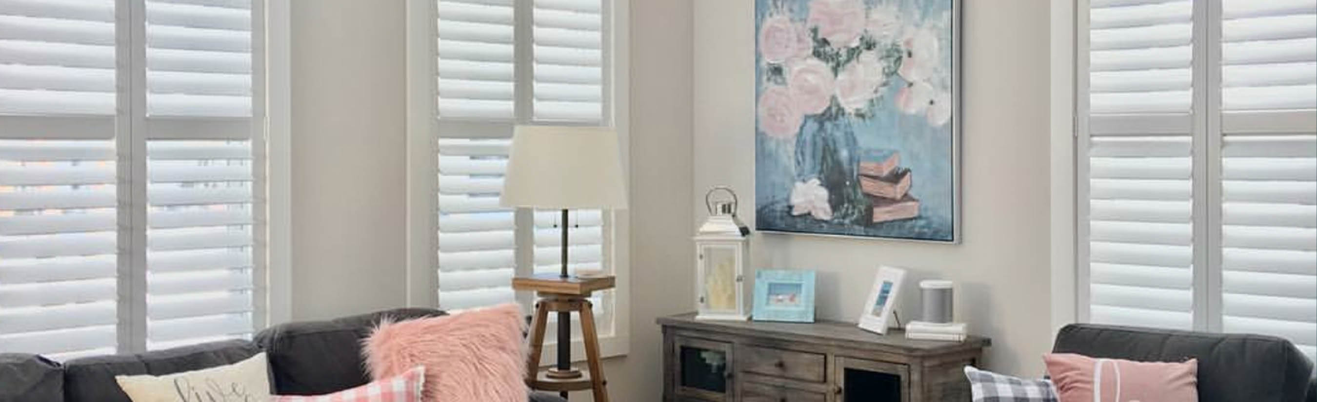 White rear mount tilt shutters in a white and pink style living room.