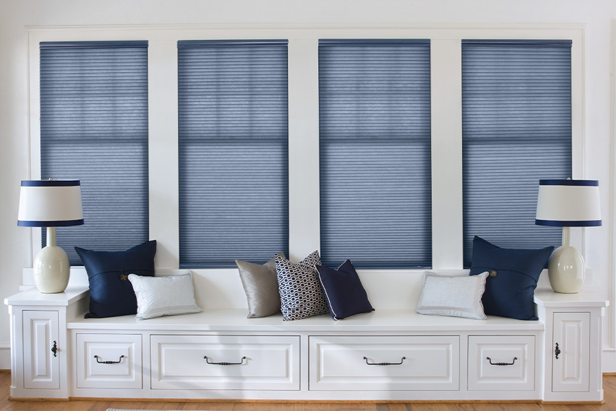 Blue roller shades by a long window seating area.