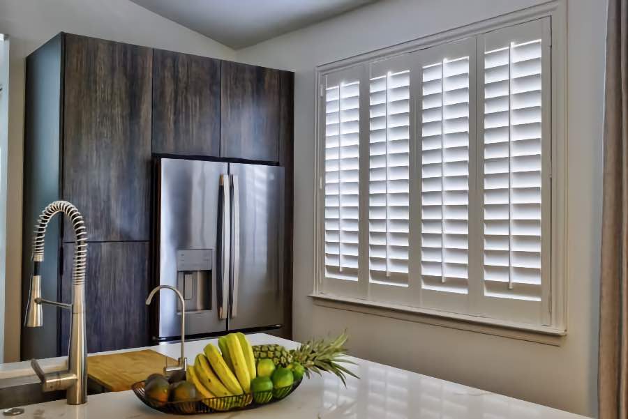 Homeowners use indoor window shutters in Tampa when they want attractive and functional window treatments. Polywood shutters on a large kitchen window