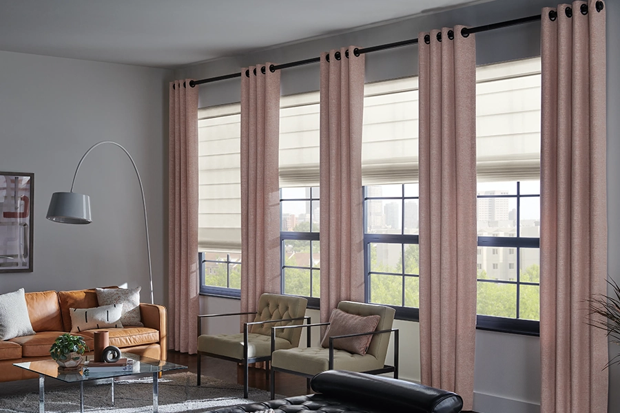Pink flowing draperies over four medium sized windows within a large living room