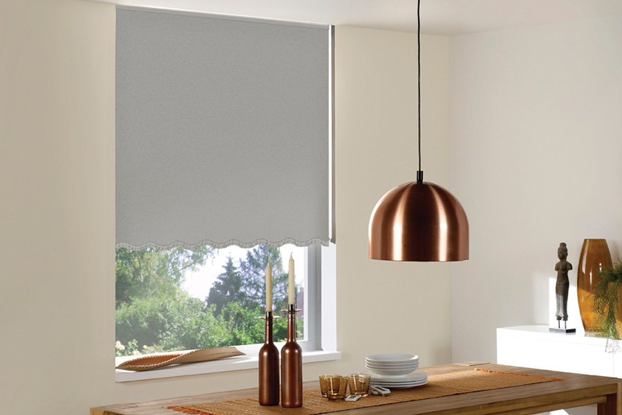 Gray roller shades with scalloped edge in a small kitchen table area.