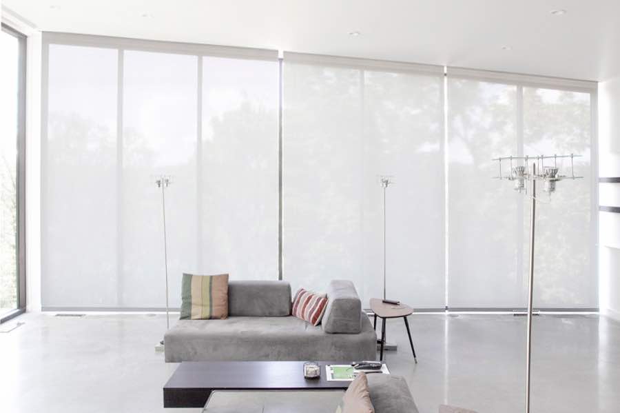 Motorized window shades make controlling natural light effortless in your Tampa great room. White motorized shades on a wall of tall great room windows