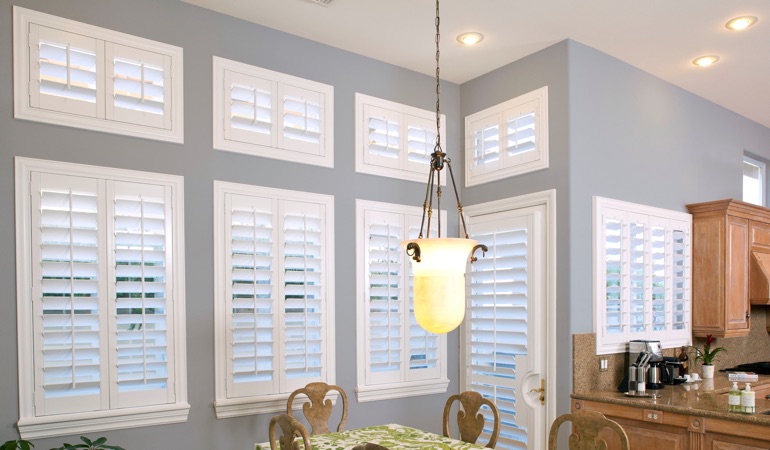 Plantation shutters can solve both sun glare and energy efficiency problems. White plantation shutters in dining room