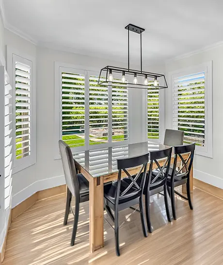 white polywood shutters in a bay window with breakfast nook table and chairs