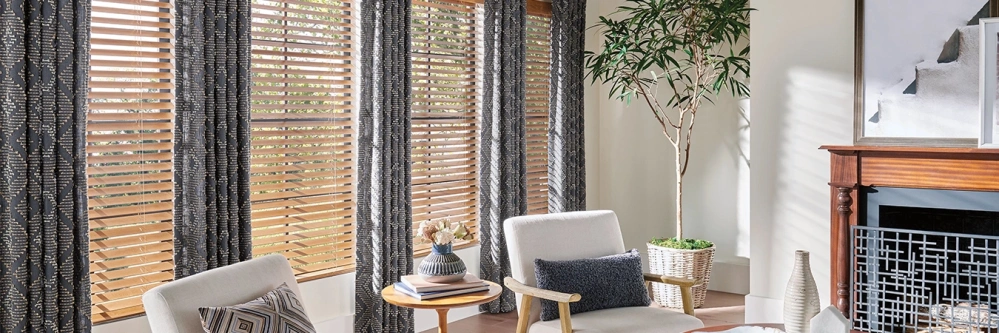 Dark patterned drapes with wood blinds on windows in a white living room