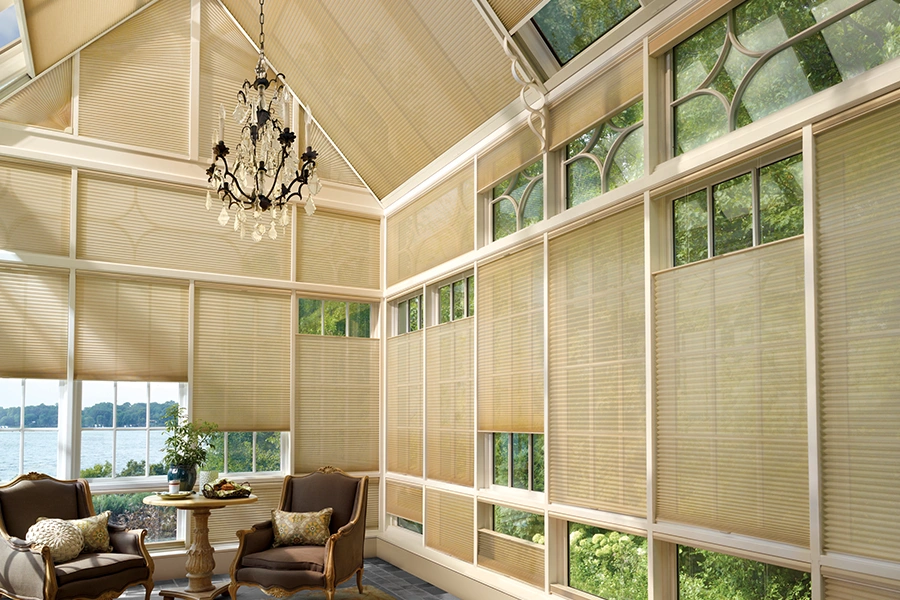 Spruce up your sunroom before summer to create a peaceful spot for relaxation. Tan window shades on windows and skylights in a large sunroom